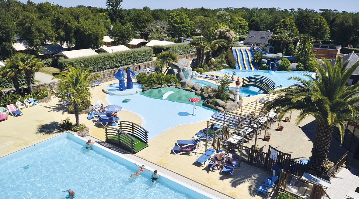 view of three swimming pools with water slides and sunbeds